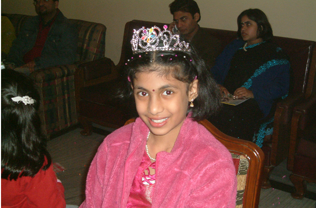a little girl wearing a tiara standing in a room
