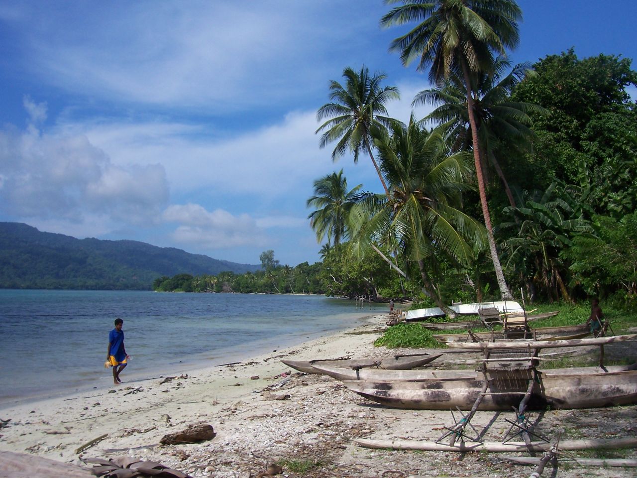 a woman standing on a beach next to canoes