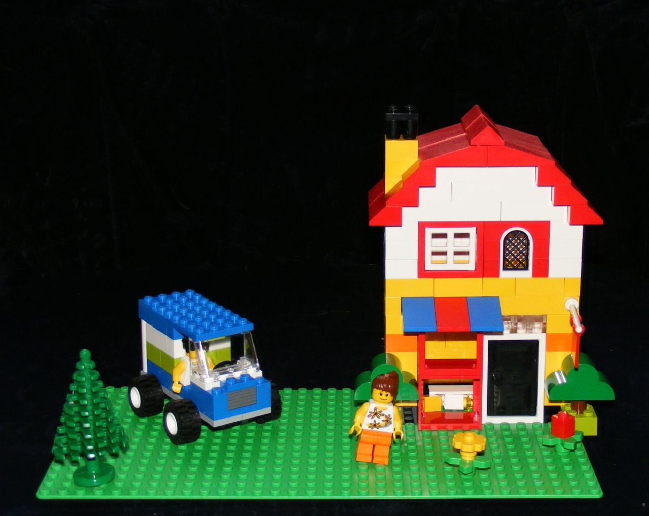 lego model house with a tractor and children's toys in front