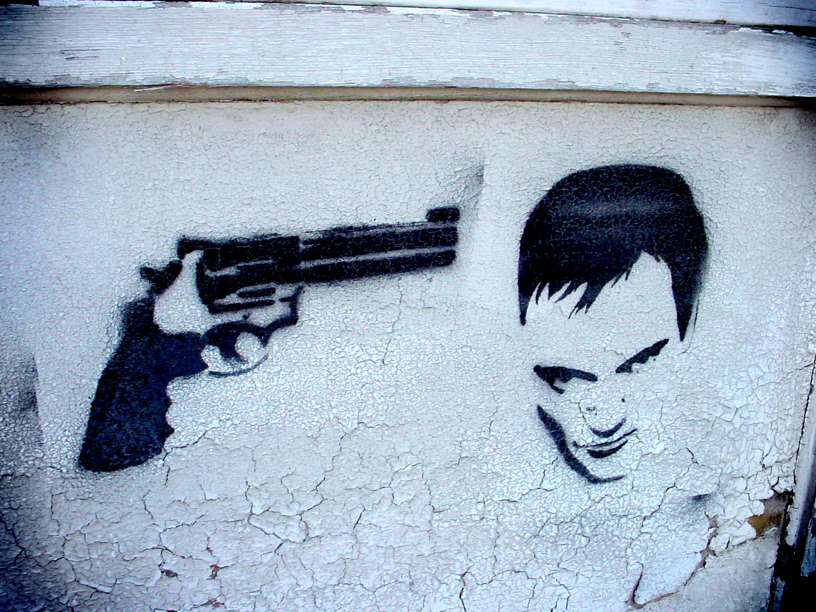 the spray - painted wall with the graffiti of the gun and a picture of the actor from the hit movie scarfp