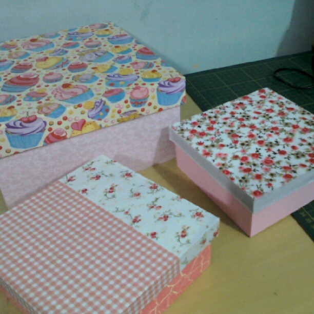 three colorful boxes sitting on a table and one is decorated with a pink flower