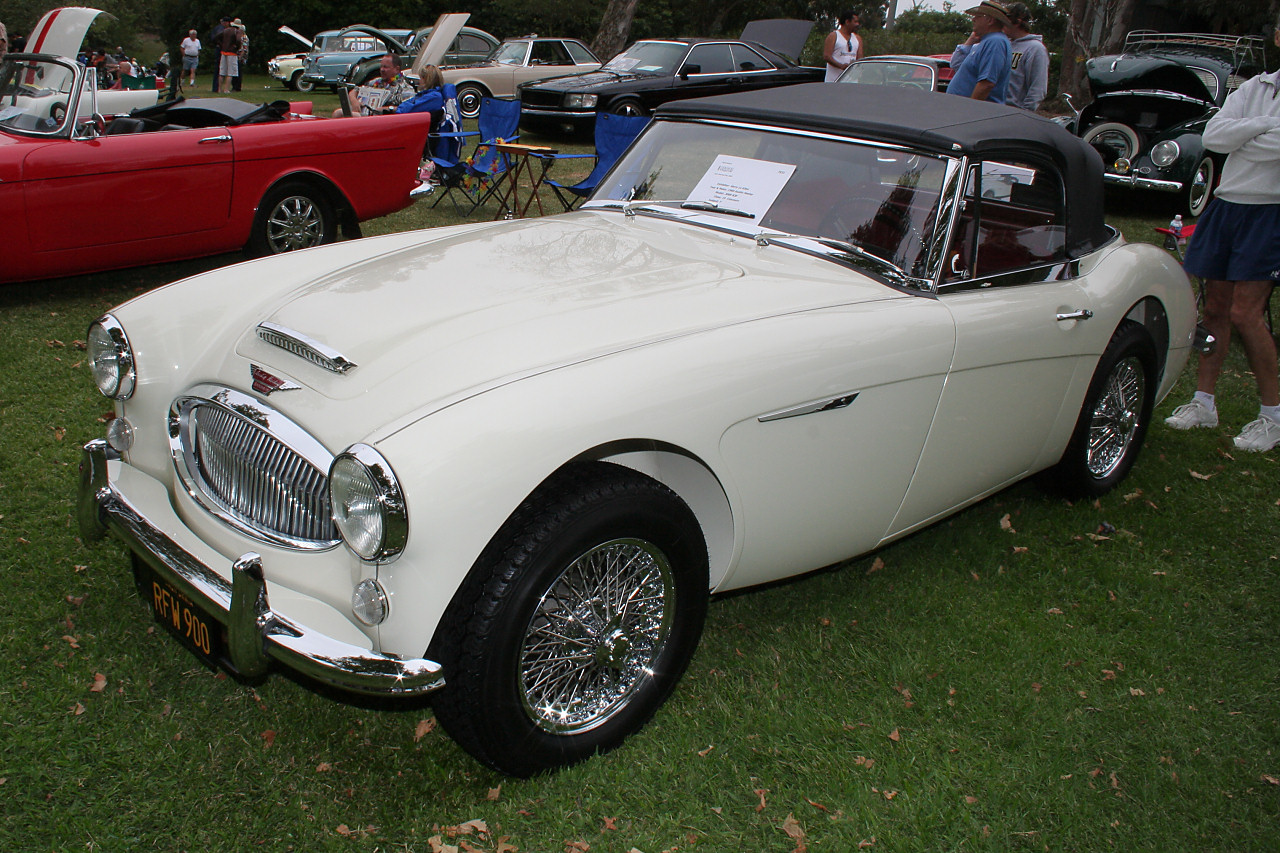 old style sports car at an event with cars parked nearby