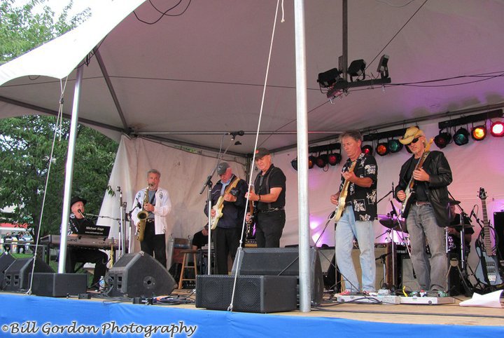 group of people standing under tent playing musical instruments