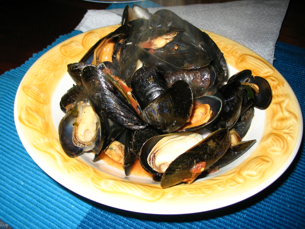 there is a white plate with mussels on it