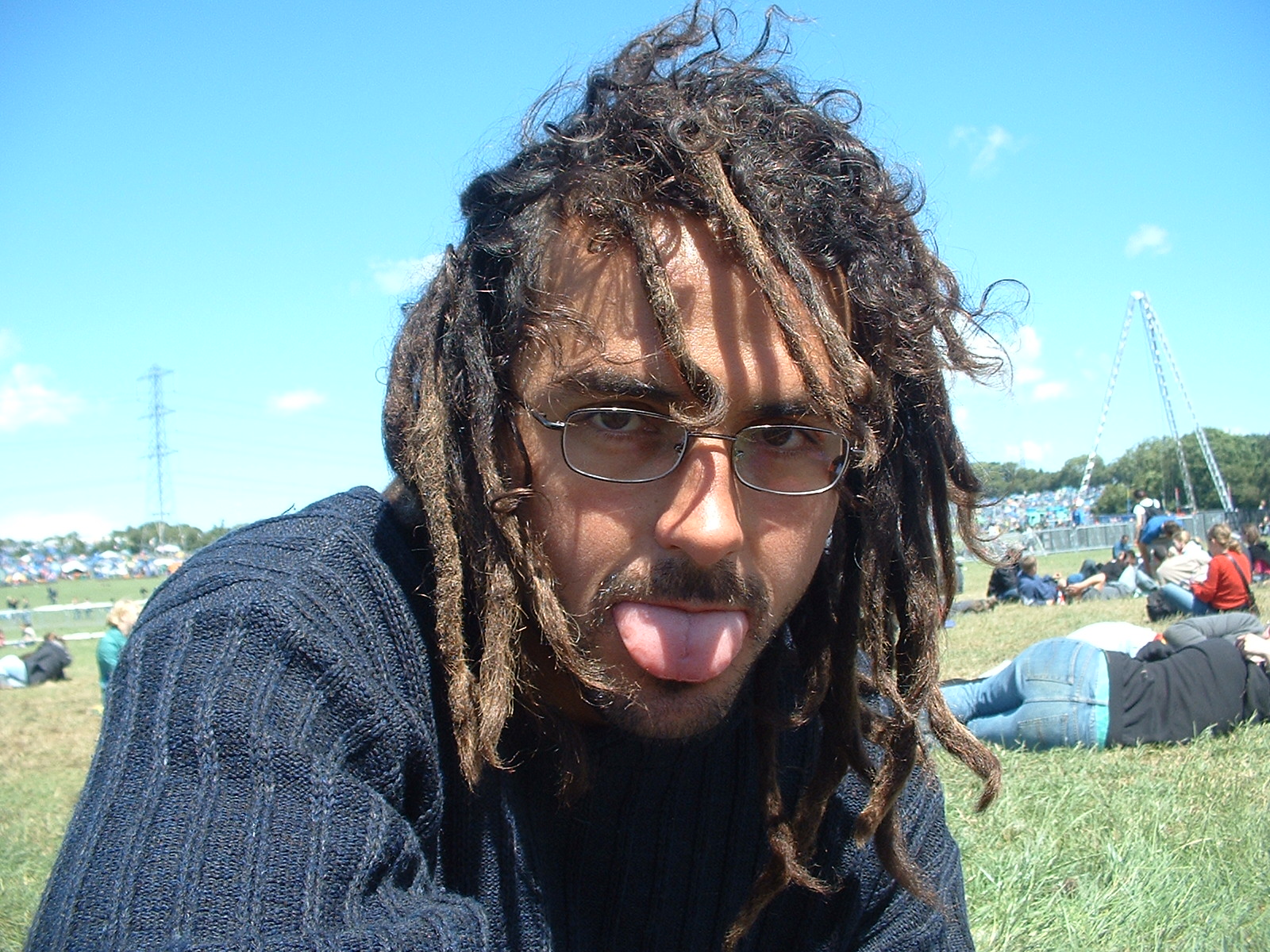 man in glasses sticking out his tongue while in the park