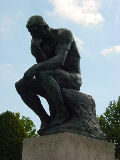 a sculpture of a man sitting on a rock