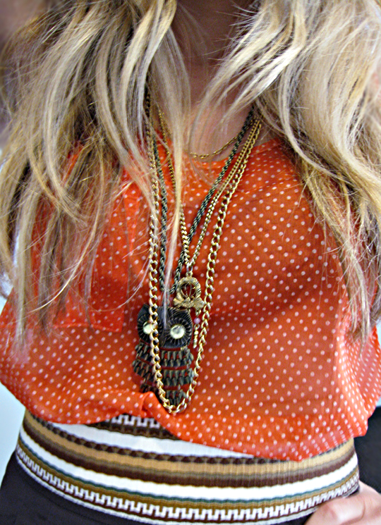 a woman wearing a necklace with a bird brooche
