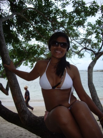 a girl in a bikini sits on a tree