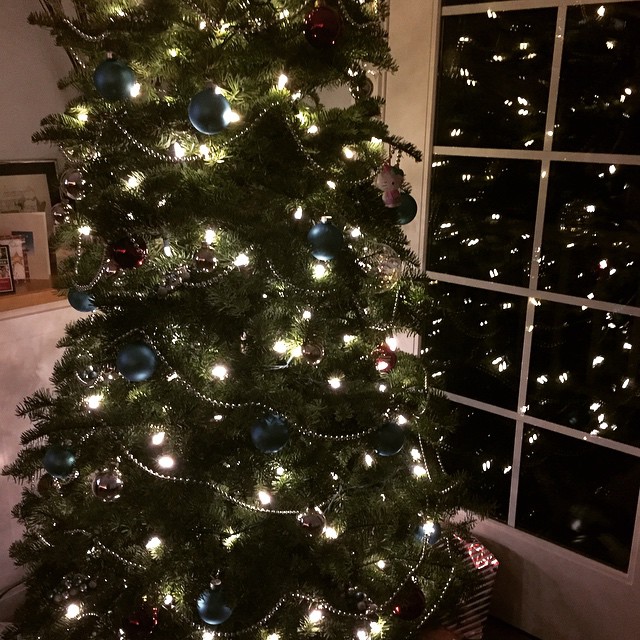 a lit christmas tree with some ornaments and presents on the floor