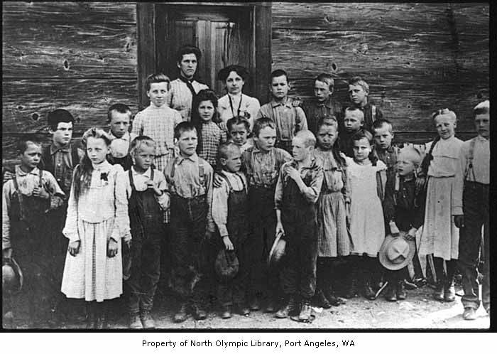 a group of children standing together in front of a wooden building