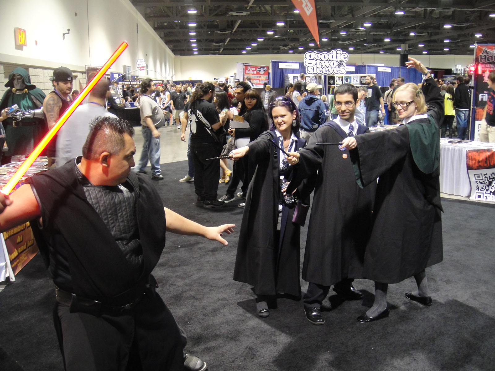 two people dressed as darth vader holding torches at an convention