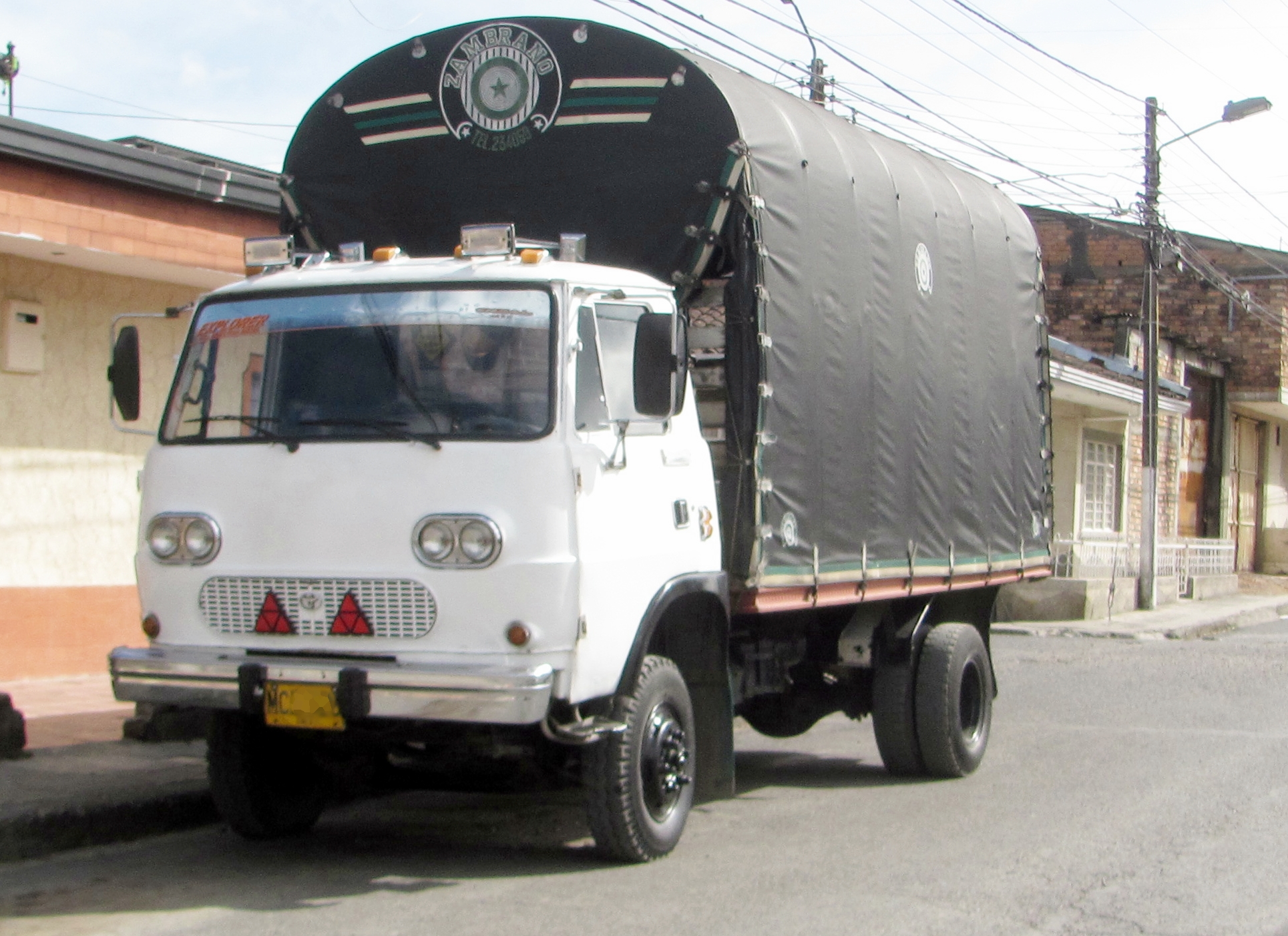 a white dump truck traveling down a street past tall buildings