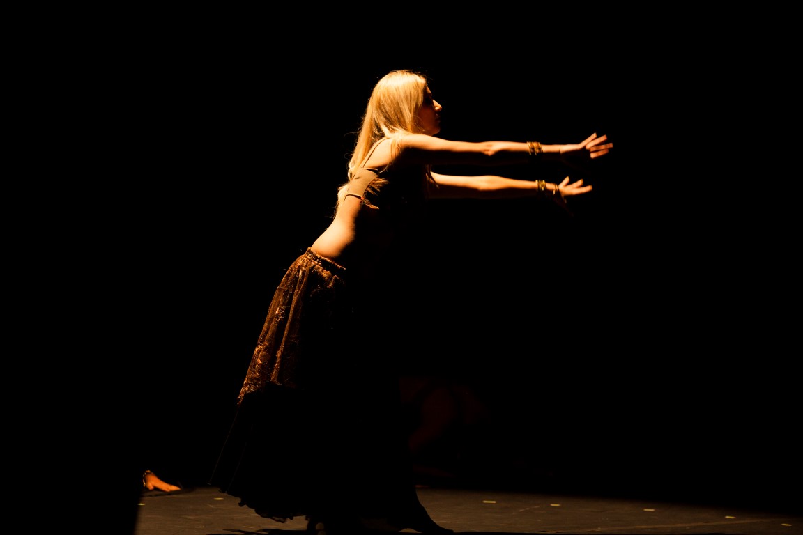 a woman in a brown dress dances on stage