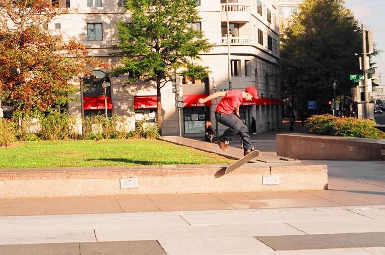 a guy on a skate board grinds on the edge of a sidewalk