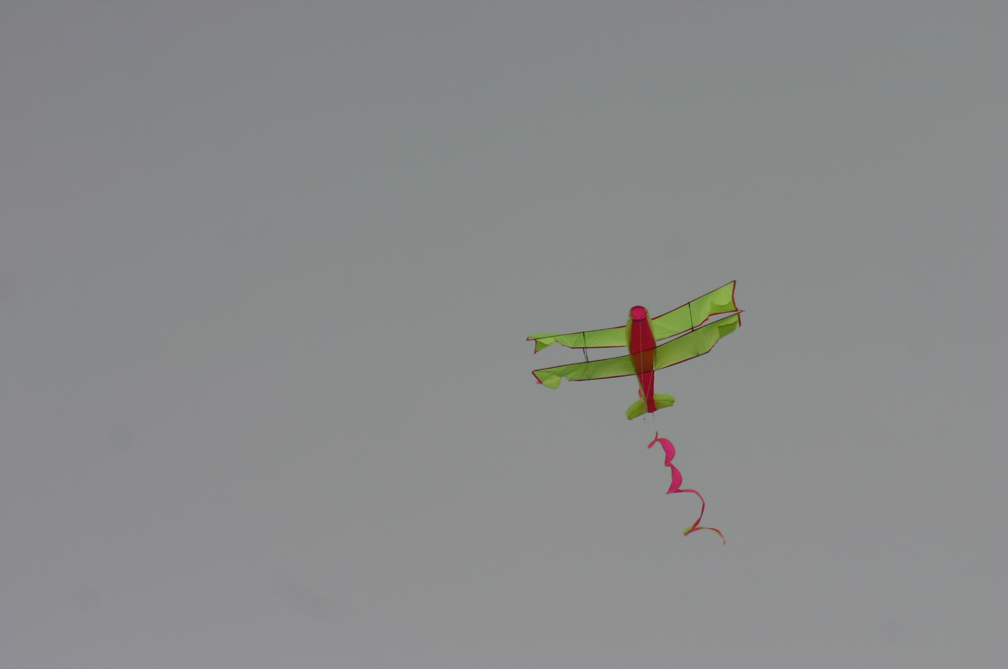 a green and red plane flying in the sky