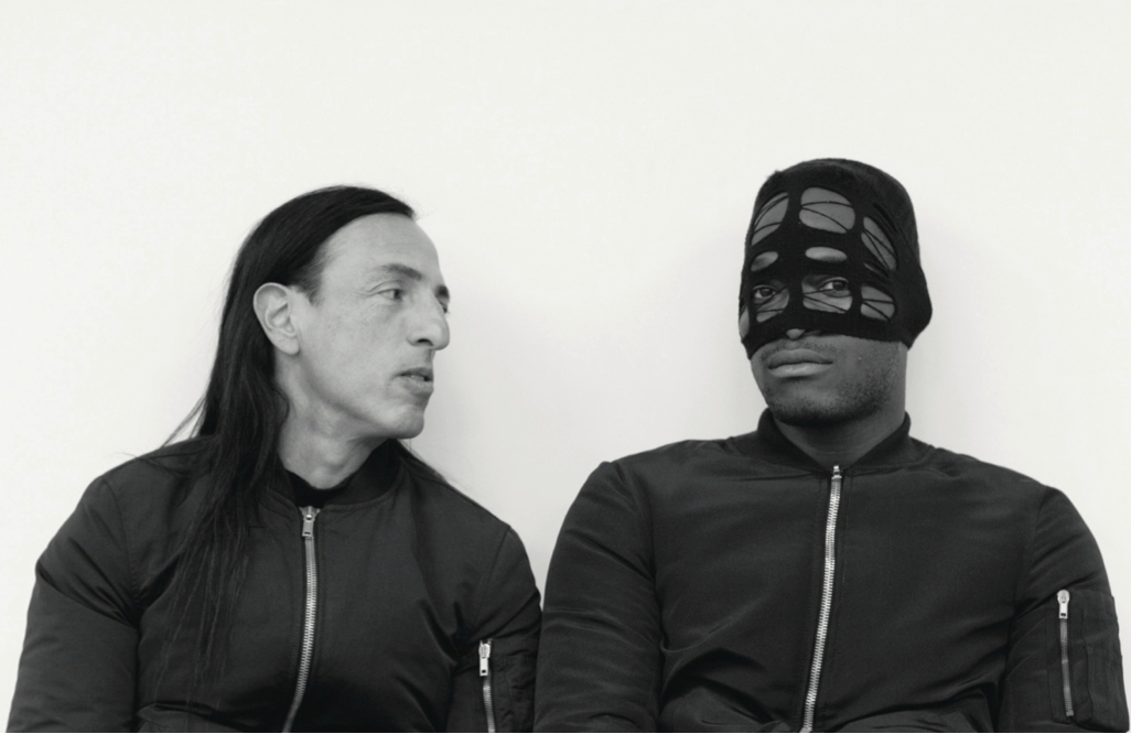 two men in hooded sweatshirts and one man in a leather mask