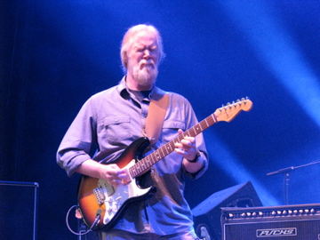 a man is holding a guitar at a concert