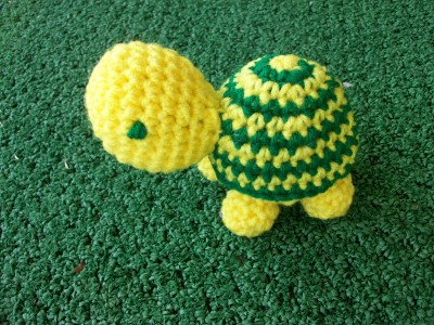 a crocheted turtle on a green surface