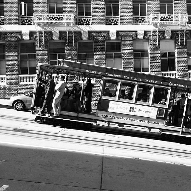 black and white po of people riding a streetcar on a street