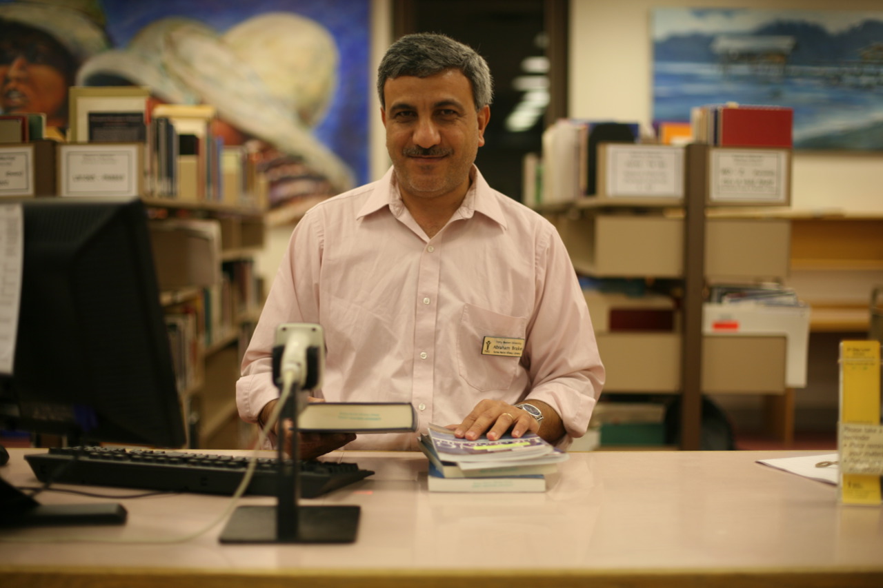 a man stands behind a desk with an assortment of books