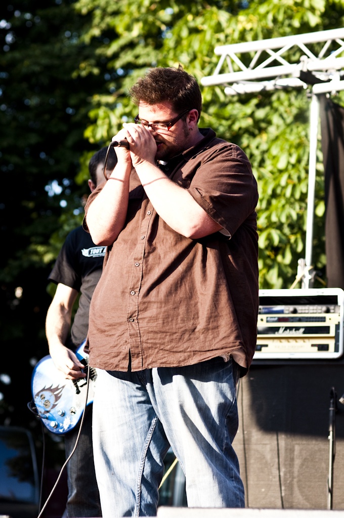 a man in a brown shirt is singing at a stage