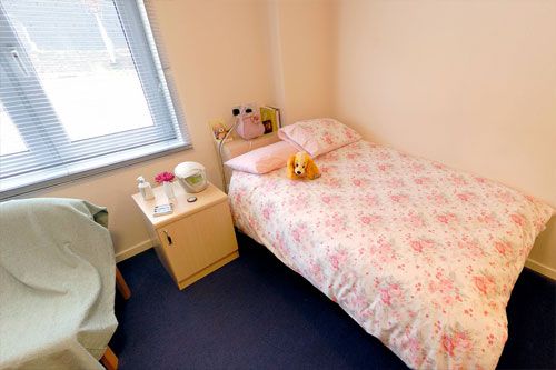 this is an empty room with a bed, table, chair and a dresser