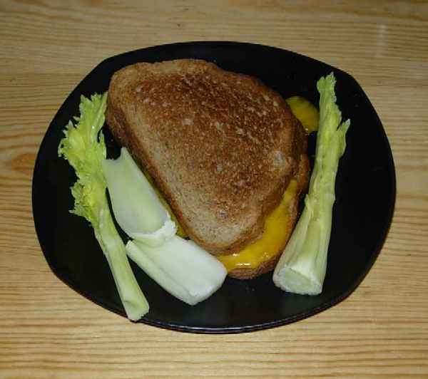 a sandwich with cheese and some celery on a black plate