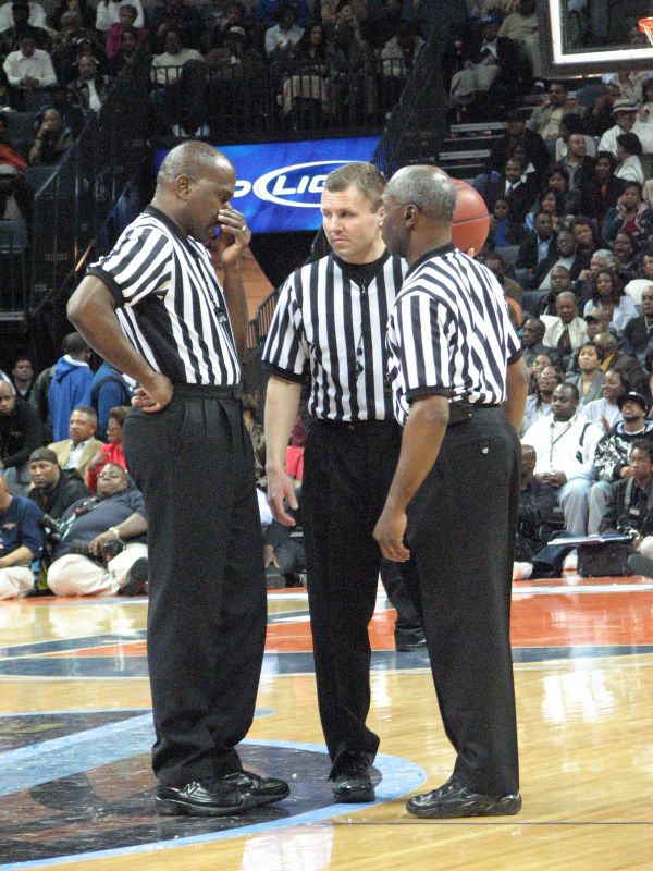 referee is talking to two men while standing on a court