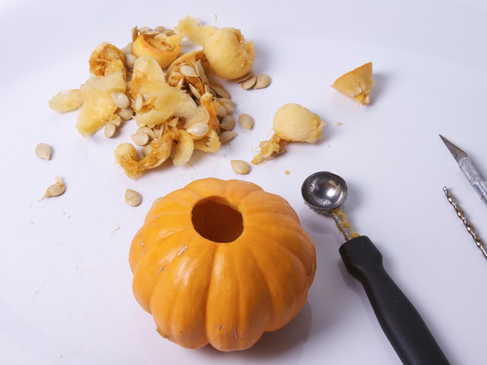 a peeled and whole pumpkin sits next to a knife on the table