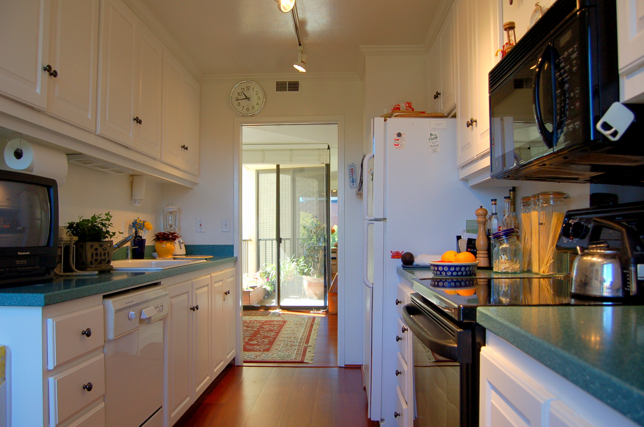 a hallway leading into a kitchen with a refrigerator and microwave