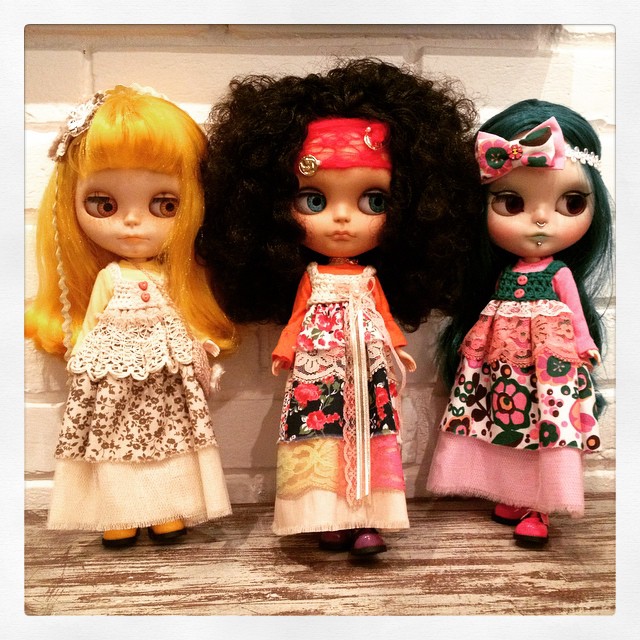 three different dolls sitting in front of a wall