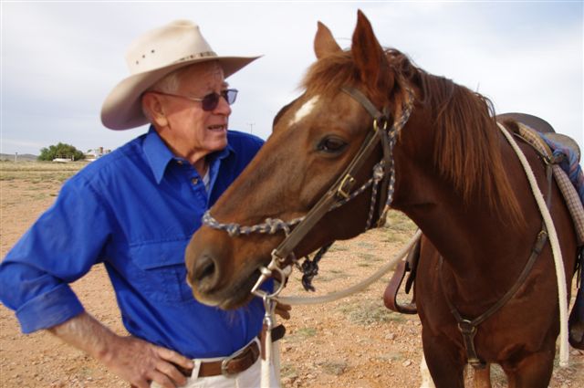 a man wearing a blue shirt with a horse near by