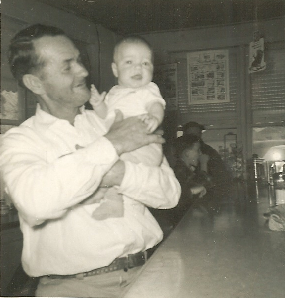 a man holding a little baby standing next to a bar