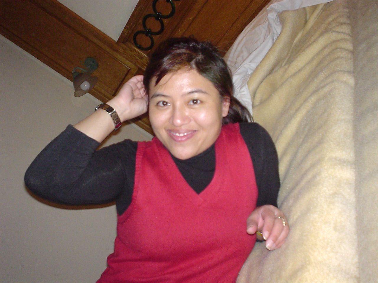 a woman in red and black shirt next to bed