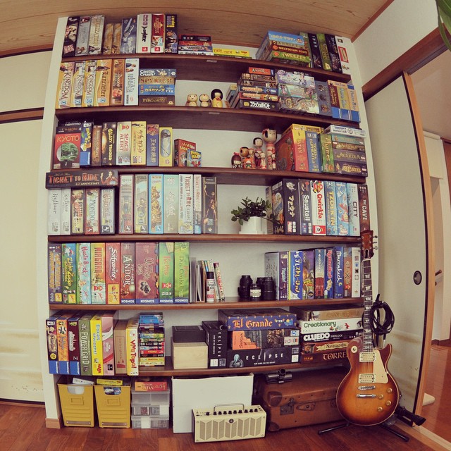 there is a book shelf with books on it and a guitar