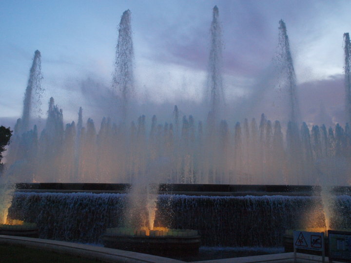 a group of fountains that are lit in the dusk