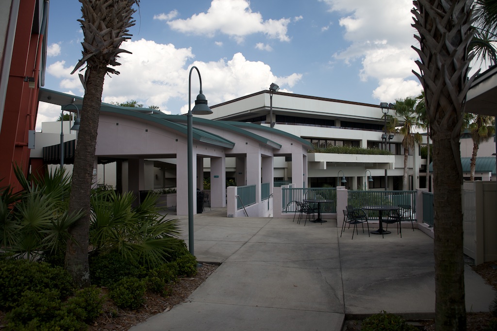 a building with a clock, palm trees and chairs around it