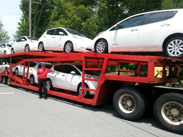 three cars on a red trailer being transported