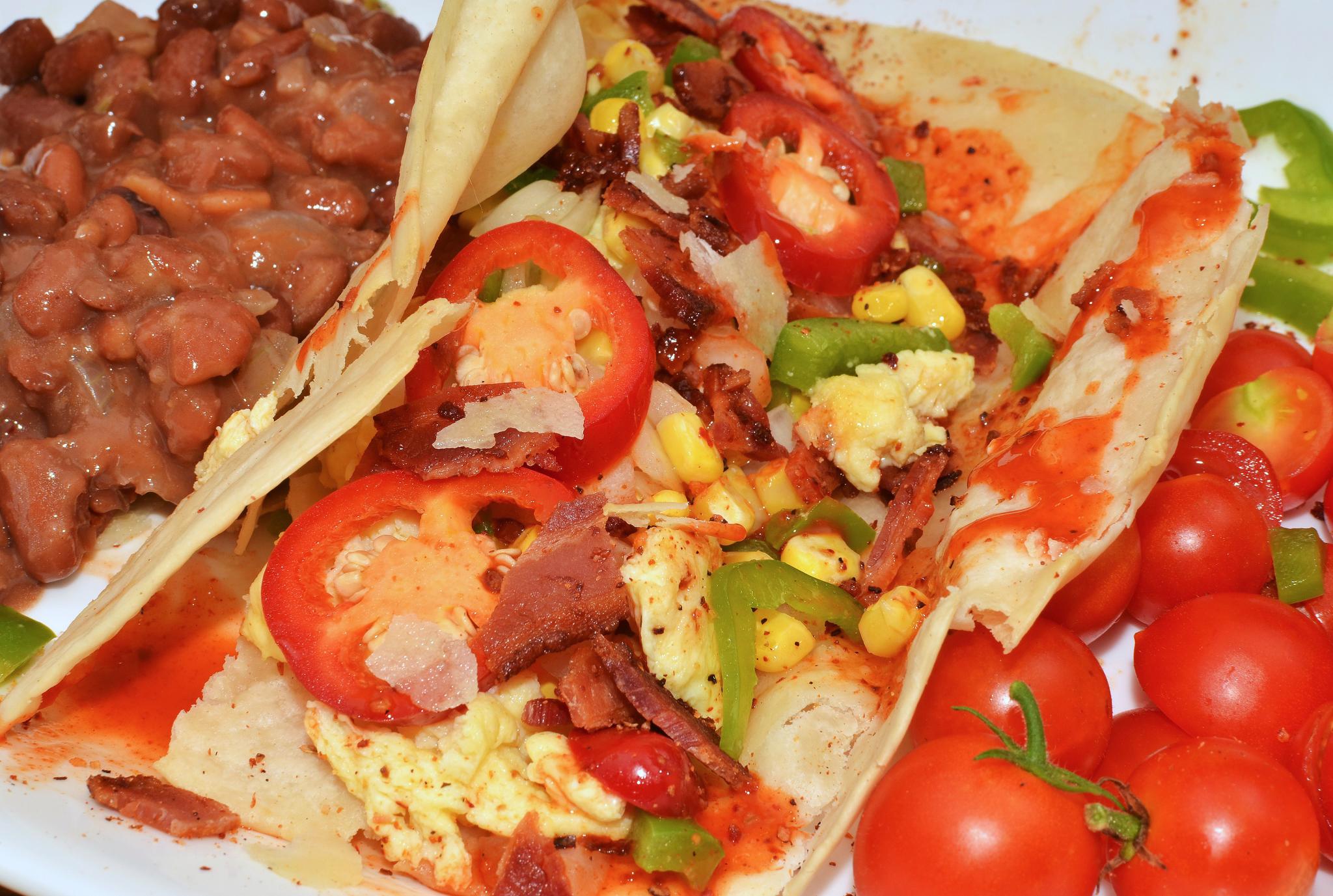 a white plate topped with two tacos and beans