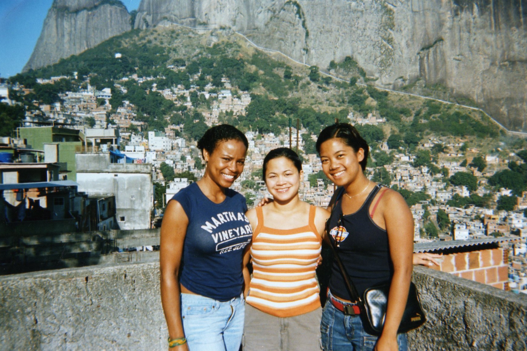 three women posing in front of a view of a town