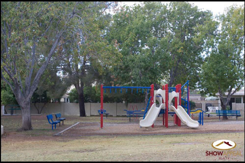 a playground area with slide and chairs and trees