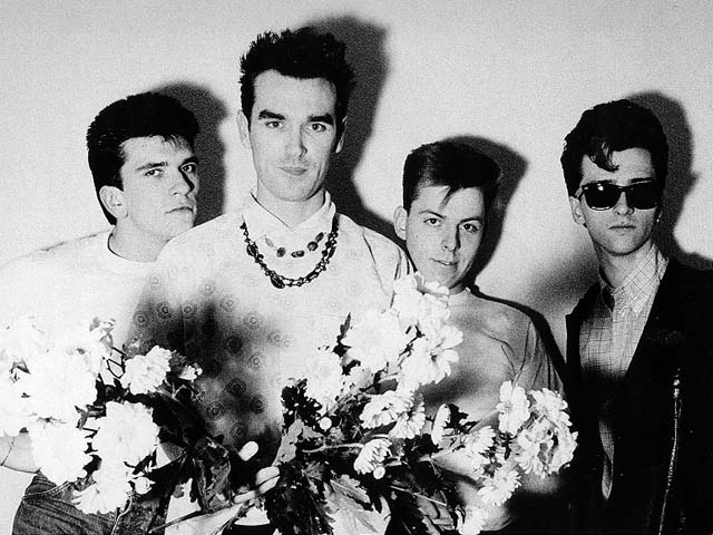 one man wearing sunglasses is holding a bouquet of flowers while standing next to three other men