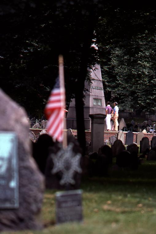 some flags are at the top of headstones in a cemetery