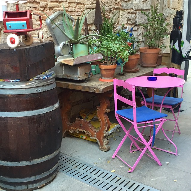 a wooden table surrounded by pink chairs next to a wooden barrel