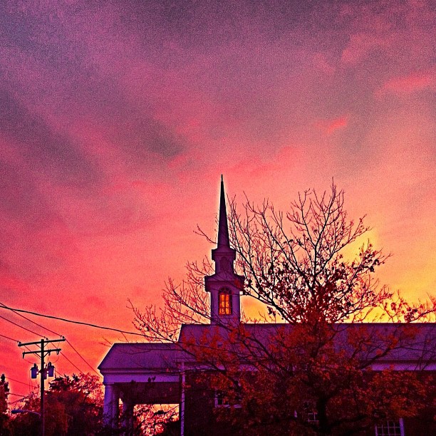 the sun sets over a church in a city