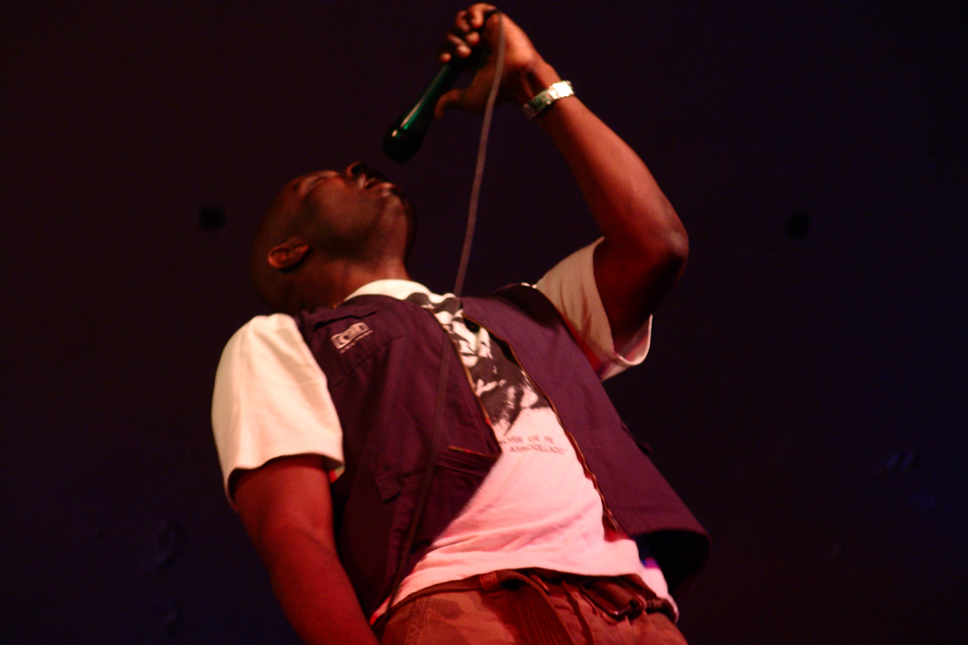 a male in a white shirt and blue vest is singing