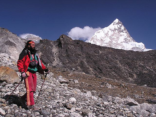 a man hiking up the side of a mountain with a snow capped peak