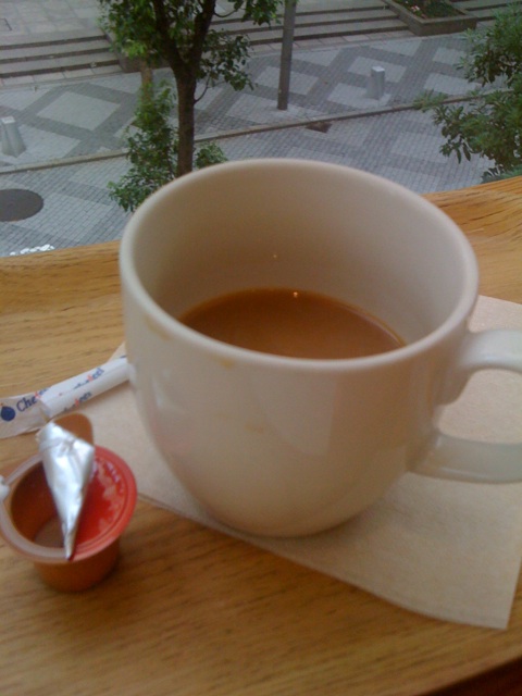 a white cup is on a saucer, next to a spoon