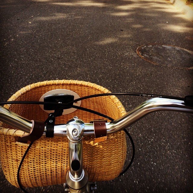 a wicker bicycle parked on the side of the road
