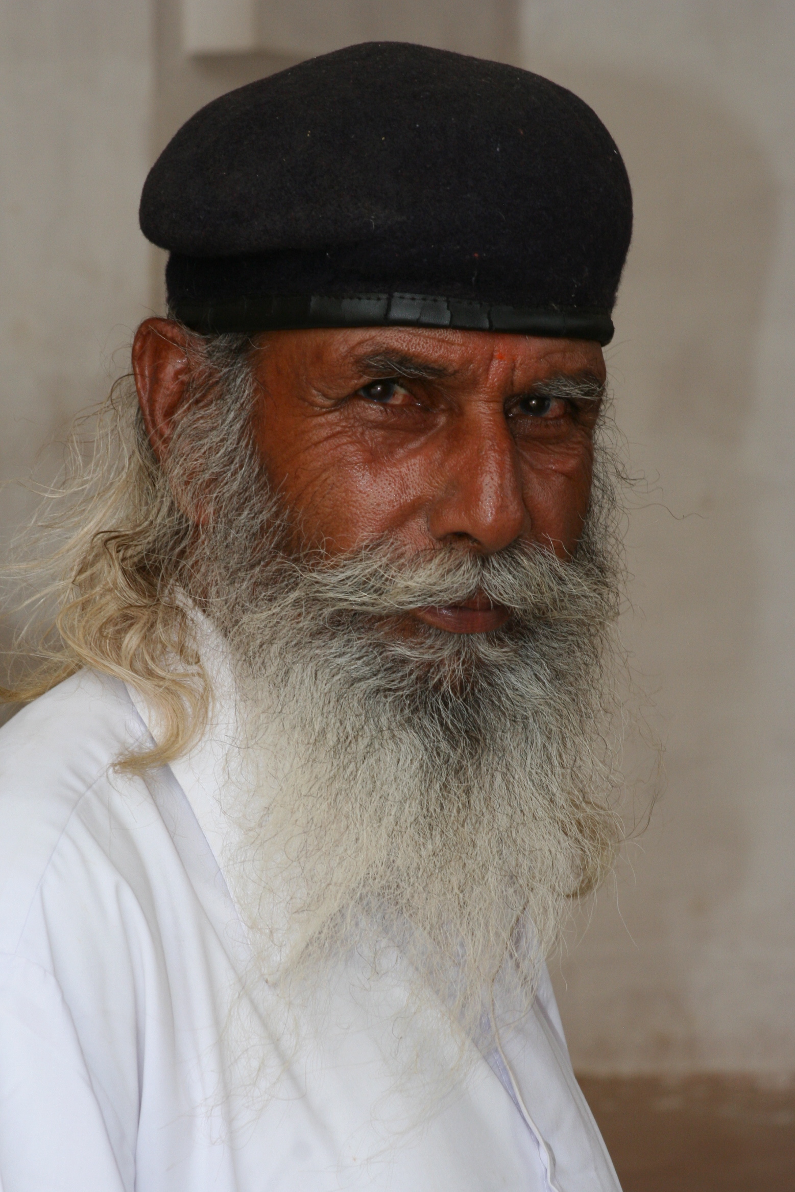 an elderly man with a white beard and a black cap